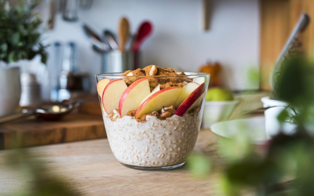 Jar of layered apple cinnamon overnight oats served with coffee.