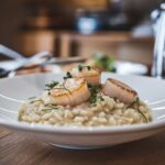 Scallop risotto served with a glass of white wine.