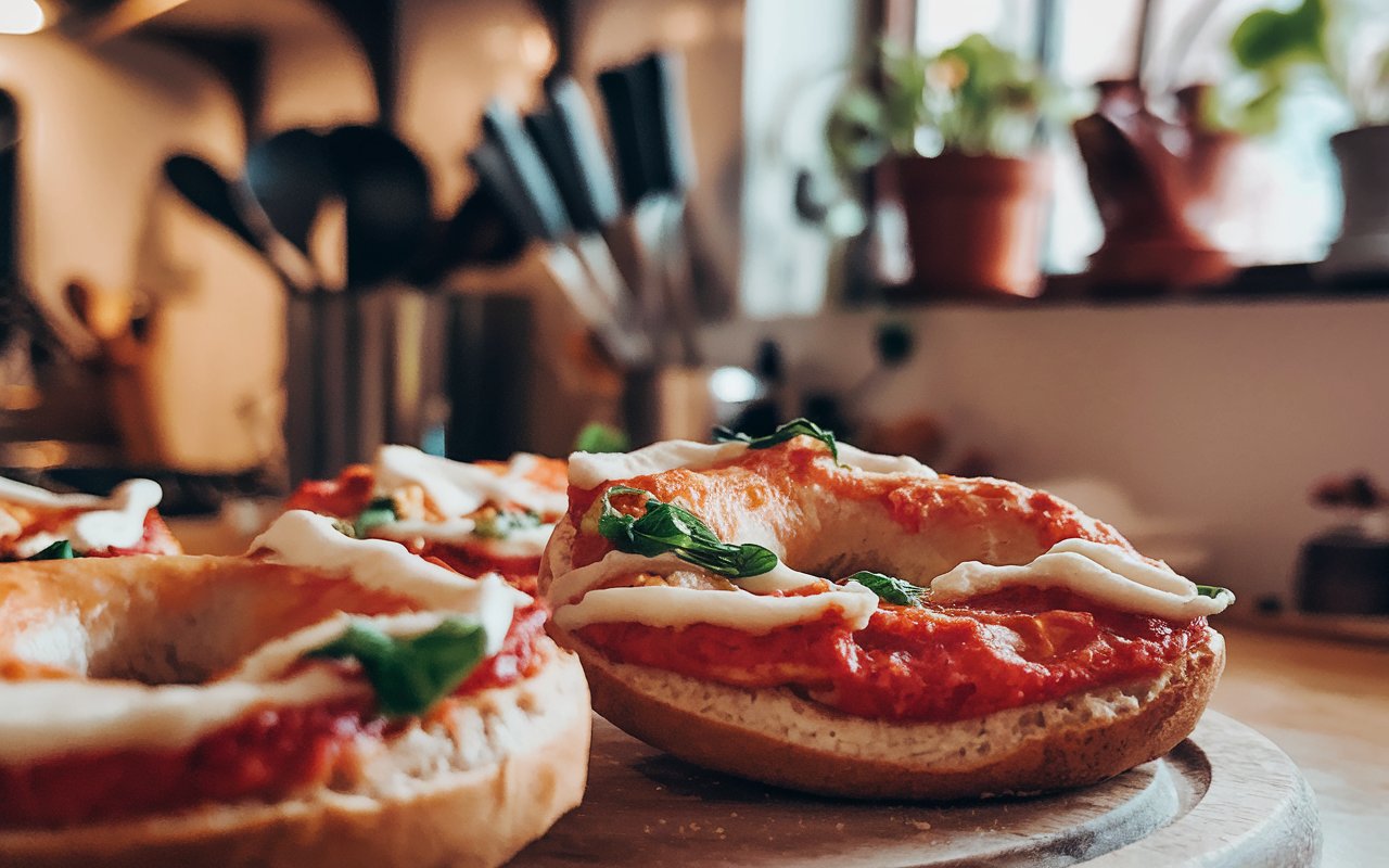  Freshly baked pizza bagels with various toppings on a wooden table.