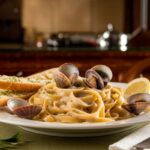 Clam Linguine paired with white wine on a rustic Italian table.